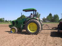 photo of Dr. John Grove in the field driving the tractor while planting soybean seed in 14 inch rows using a Lilliston drill