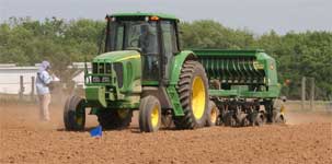 photo showing research intern assisting tractor operator with proper row alignment while using the drill planter