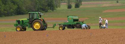 photo showing the tractor paused in field while the team checks the planter adjustments 