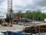 The rack of drill pipe, drilling motor (yellow), and automatic pipe handling and other equipment in use at the well site.