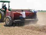 photo of tractor and planter with workers watching seed flow
