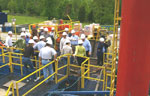 Participants stand on walkways above the mud tanks as Donald Strehle describes the operation.