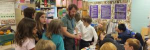 Photo of a student teacher working in a middle school art classroom with children.