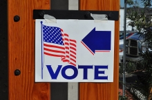 "Vote" sign with American flag and an arrow