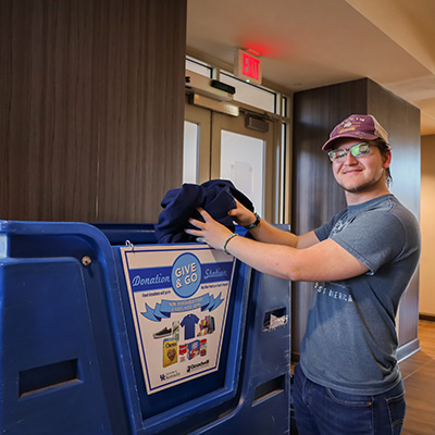 A University of Kentucky student donating unwanted clothing to the Give and Go Donation Stations.