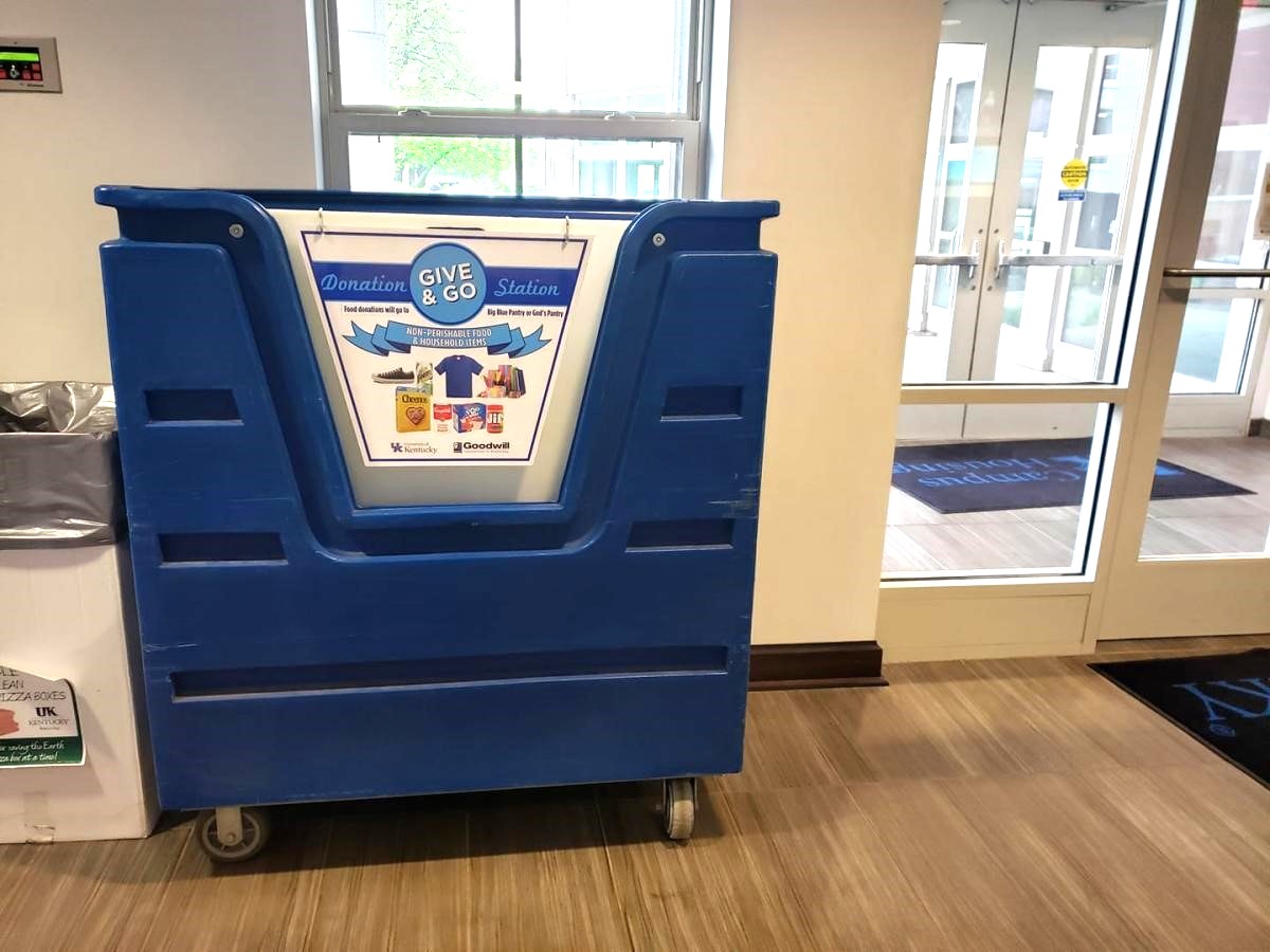 a blue bin with a sign that says Give and Go Donation Station in a building