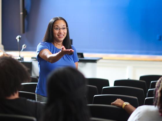 Female faculty member with her hand out teaching a class